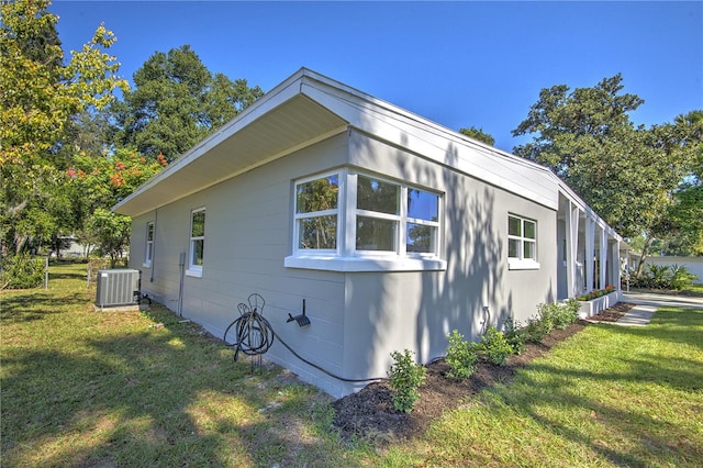 view of side of home with central AC unit and a lawn