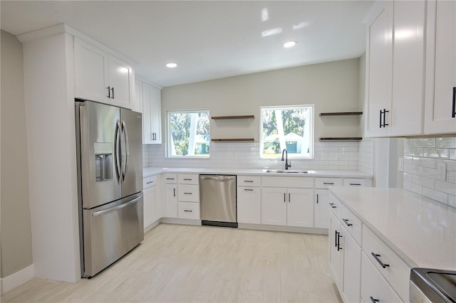 kitchen with decorative backsplash, white cabinetry, light wood-type flooring, sink, and stainless steel appliances