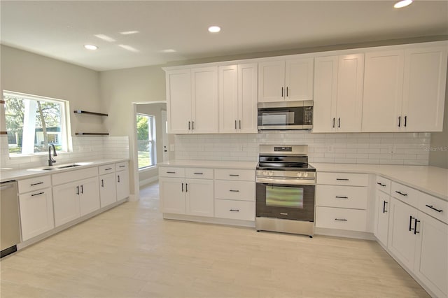 kitchen with appliances with stainless steel finishes, sink, plenty of natural light, and white cabinets