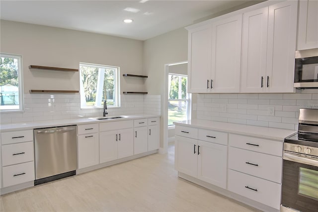 kitchen featuring white cabinets, backsplash, appliances with stainless steel finishes, light hardwood / wood-style floors, and sink