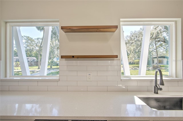 kitchen with sink, light stone countertops, and backsplash