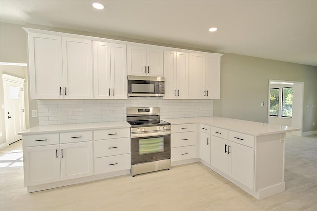 kitchen featuring appliances with stainless steel finishes, kitchen peninsula, white cabinets, and tasteful backsplash