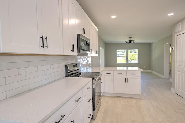 kitchen with appliances with stainless steel finishes, kitchen peninsula, light hardwood / wood-style floors, white cabinets, and decorative backsplash