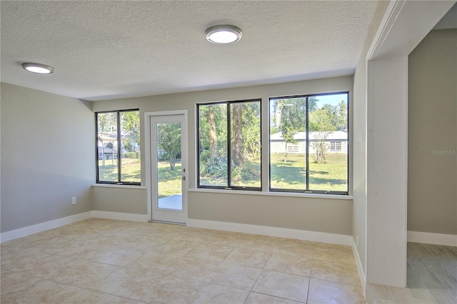 tiled empty room with a textured ceiling