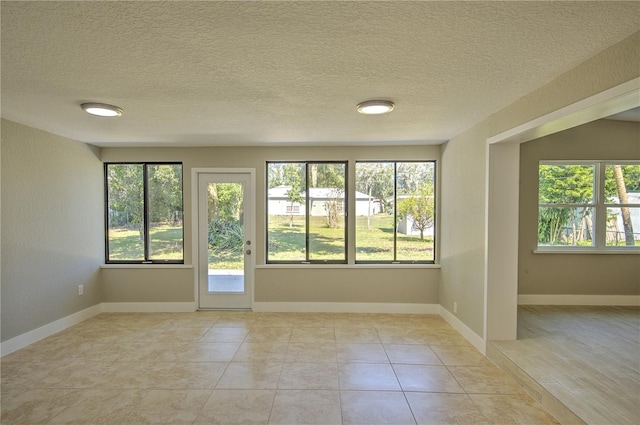 spare room with a textured ceiling and light tile patterned floors