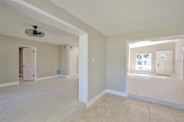 spare room featuring a textured ceiling and light hardwood / wood-style flooring