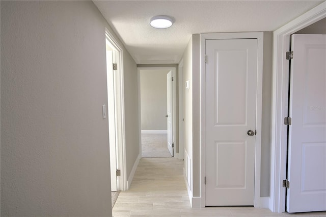 hallway featuring light hardwood / wood-style flooring and a textured ceiling