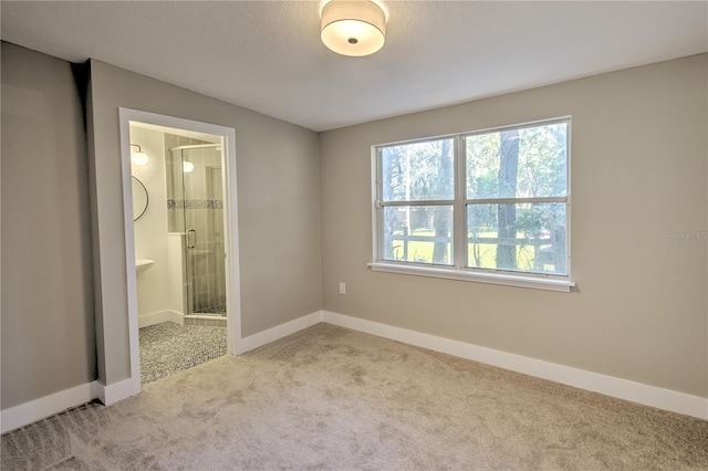 unfurnished bedroom with connected bathroom, a textured ceiling, and light colored carpet