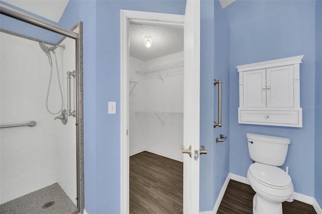 2204 Clementine Trl, Clermont, FL 34714 - bathroom with a stall shower, wood finished floors, toilet, a walk in closet, and baseboards