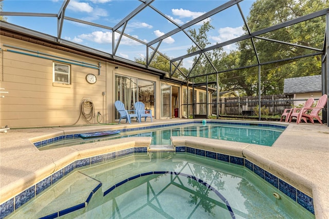 view of pool with a patio area, an in ground hot tub, and glass enclosure