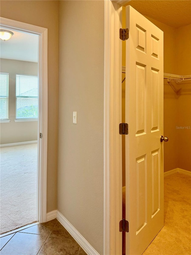 hallway with light colored carpet and a textured ceiling