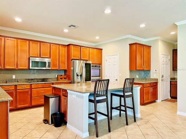 kitchen with a kitchen breakfast bar, a center island, light stone counters, and stainless steel appliances