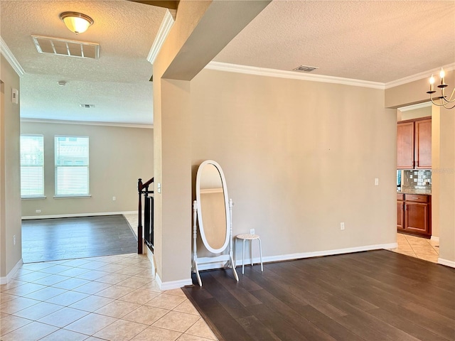 unfurnished room with light hardwood / wood-style floors, ornamental molding, and a textured ceiling