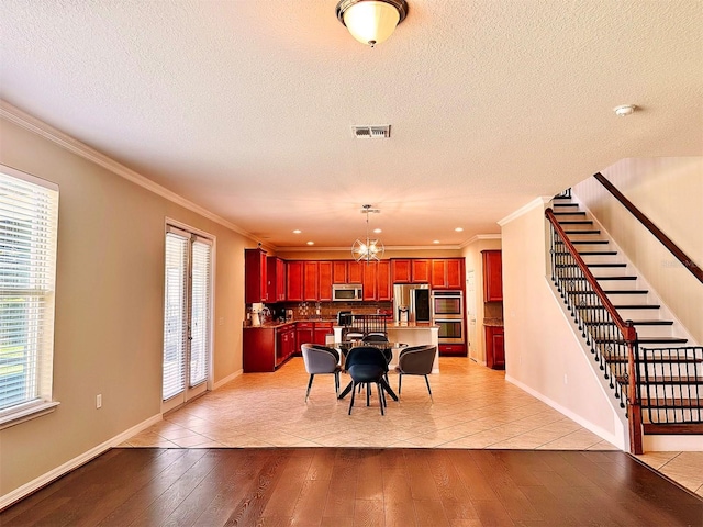 dining area with a textured ceiling, light hardwood / wood-style floors, and ornamental molding