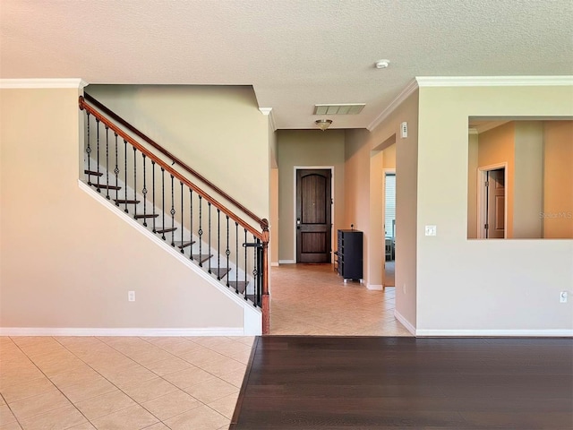 entryway featuring light hardwood / wood-style floors, ornamental molding, and a textured ceiling