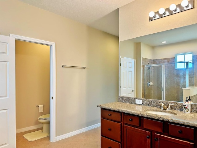 bathroom with a textured ceiling, vanity, toilet, and a shower with door