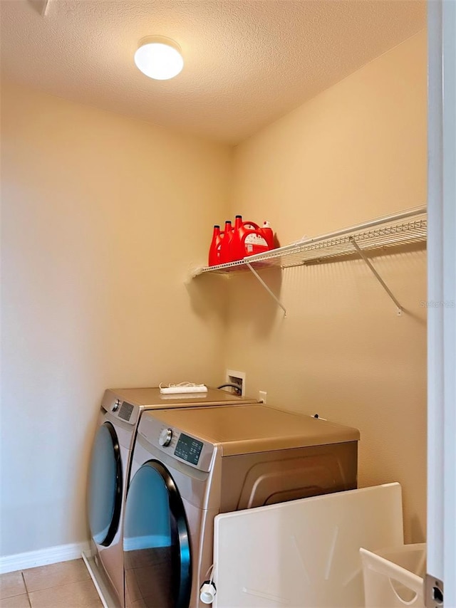 clothes washing area with light tile patterned floors, a textured ceiling, and washer and clothes dryer