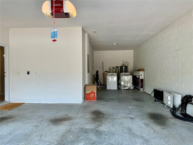 garage featuring electric water heater, a garage door opener, and washing machine and dryer