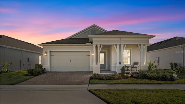 view of front of property featuring driveway, covered porch, a front yard, stucco siding, and a garage