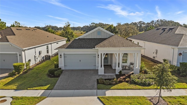 ranch-style home featuring a porch, a front lawn, a garage, driveway, and central AC