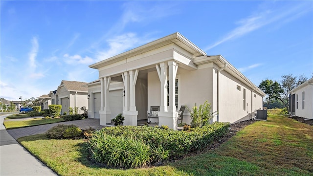 view of side of property with driveway, a yard, stucco siding, central AC, and a garage
