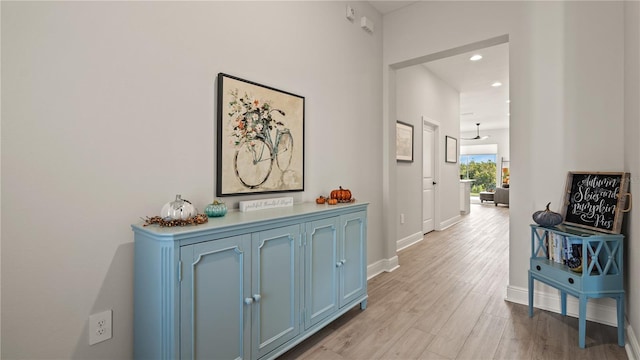 corridor featuring light wood finished floors, recessed lighting, and baseboards