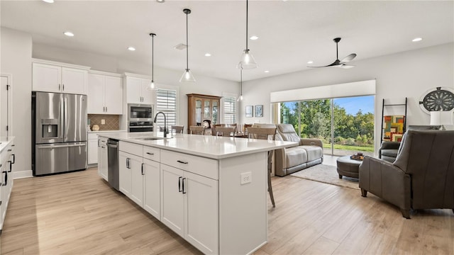 kitchen with white cabinetry, appliances with stainless steel finishes, sink, and a center island with sink