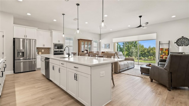 kitchen featuring open floor plan, stainless steel appliances, light wood-type flooring, and a sink