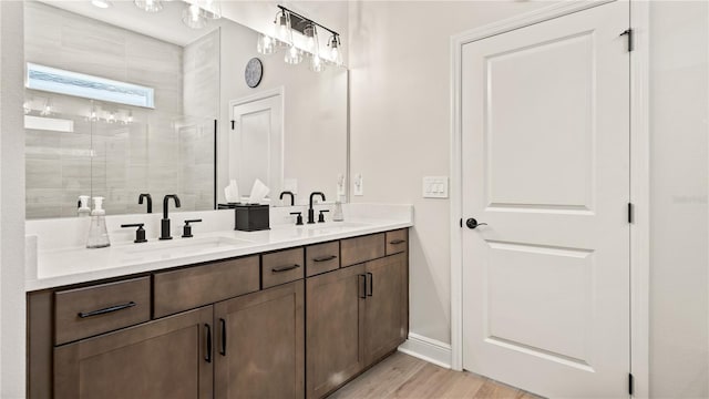 full bath with double vanity, wood finished floors, a shower stall, and a sink