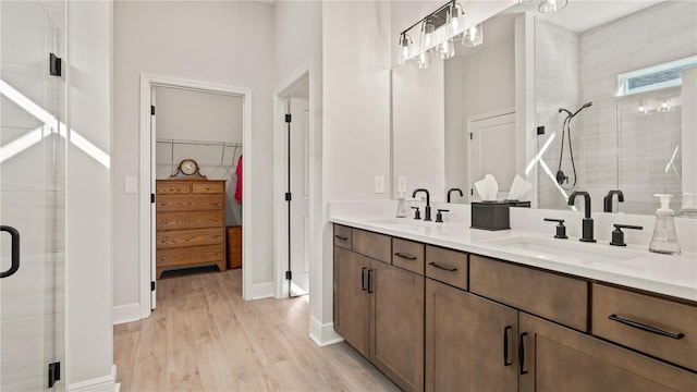full bath with a sink, a shower stall, wood finished floors, and a spacious closet