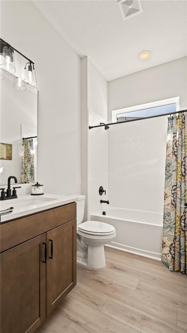 full bath with wood finished floors, shower / bathtub combination with curtain, toilet, vanity, and visible vents