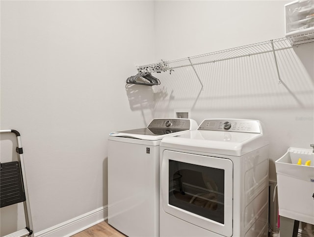 laundry room featuring light hardwood / wood-style flooring, washing machine and dryer, and sink