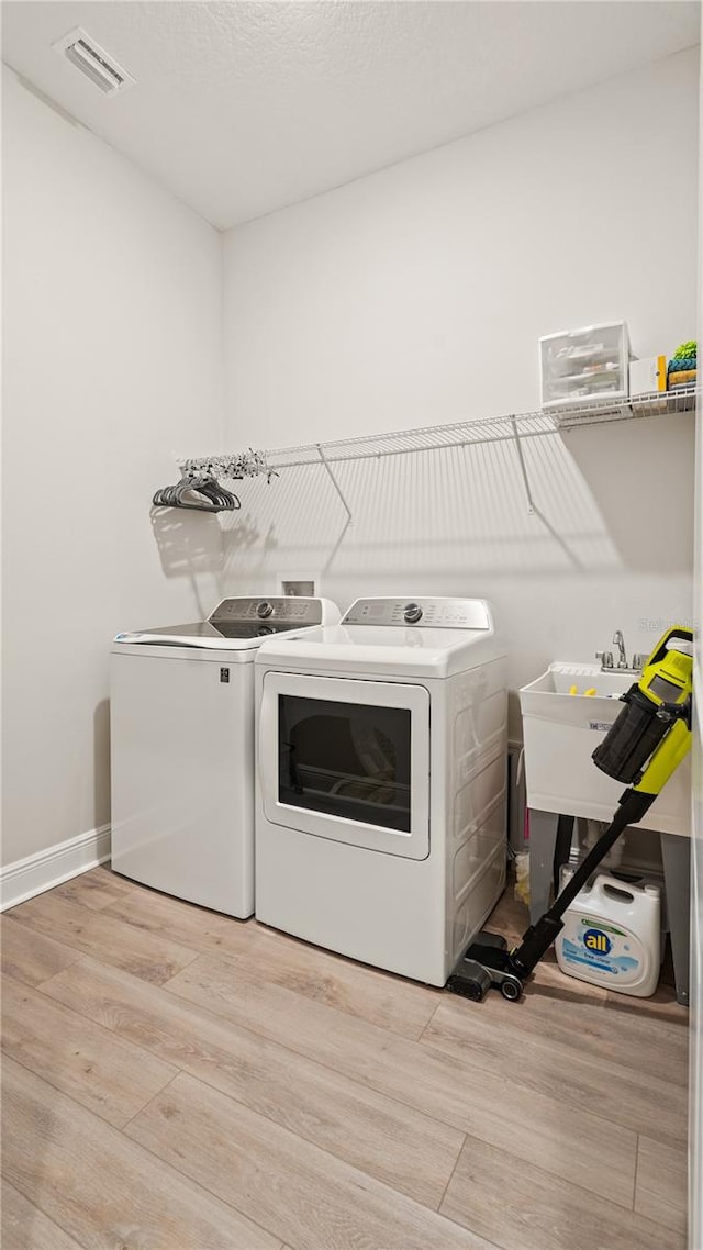 clothes washing area featuring independent washer and dryer and light hardwood / wood-style floors