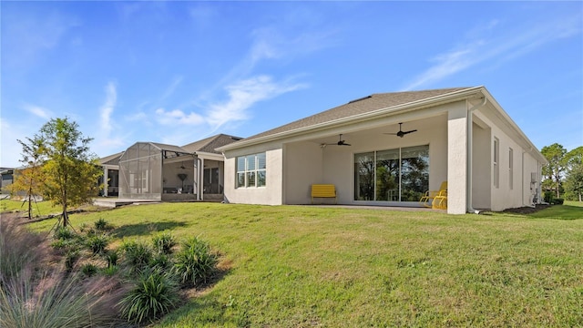 back of property featuring a lawn, ceiling fan, and stucco siding
