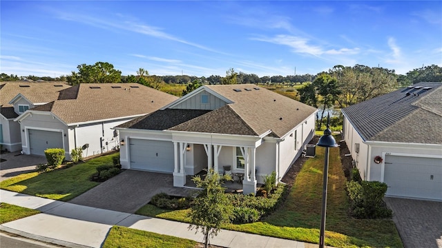 single story home featuring a porch, stucco siding, decorative driveway, a front lawn, and an attached garage