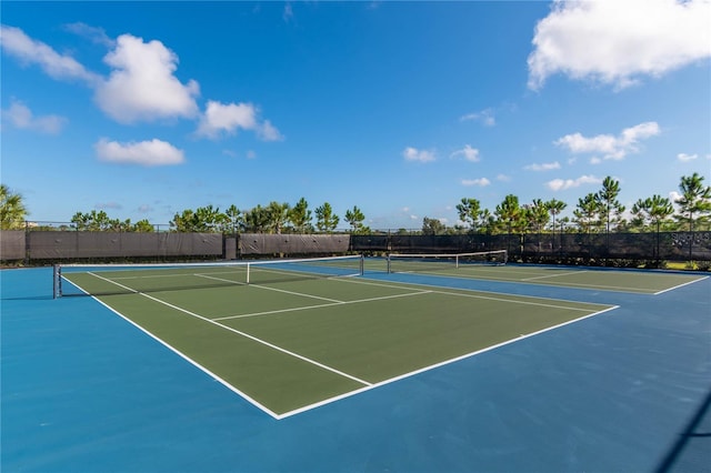 view of tennis court featuring community basketball court and fence