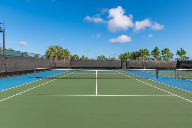 view of tennis court featuring community basketball court and fence