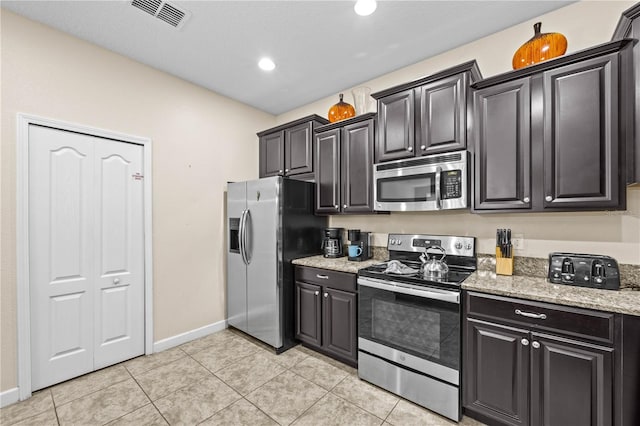 1473 Moon Valley Dr, Davenport, FL 33896 - kitchen featuring appliances with stainless steel finishes, light tile patterned floors, baseboards, light stone counters, and dark cabinetry