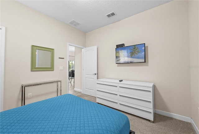 bedroom featuring light carpet and a textured ceiling