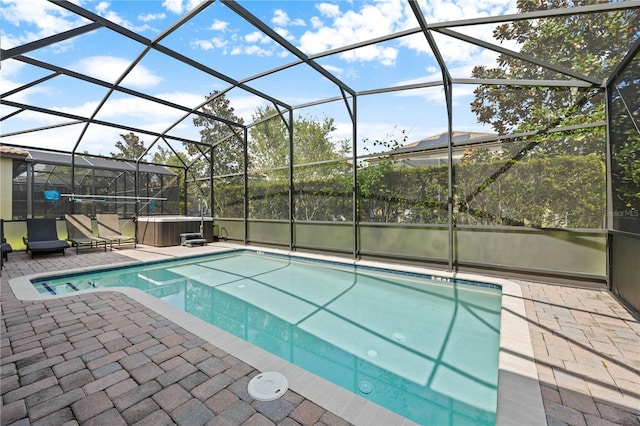 view of pool with a patio, glass enclosure, and a hot tub