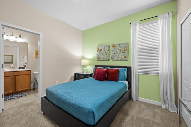 bedroom featuring light carpet, sink, and ensuite bathroom