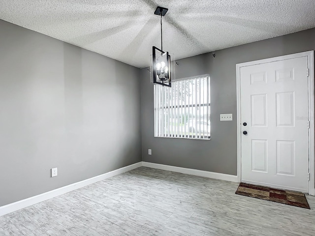 unfurnished dining area featuring a notable chandelier, hardwood / wood-style floors, and a textured ceiling