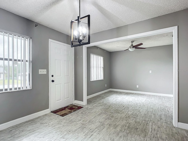 entrance foyer featuring ceiling fan with notable chandelier, a textured ceiling, and light hardwood / wood-style flooring