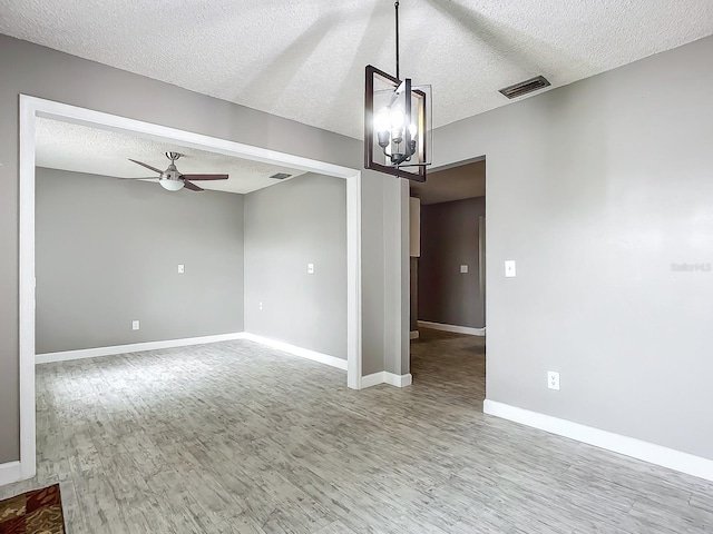 unfurnished room with hardwood / wood-style flooring, ceiling fan with notable chandelier, and a textured ceiling