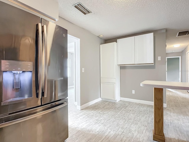 kitchen featuring light hardwood / wood-style flooring, white cabinets, a textured ceiling, and stainless steel fridge with ice dispenser