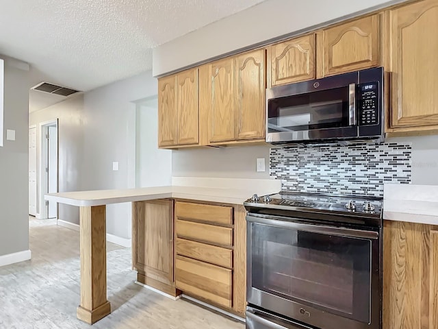 kitchen with stainless steel electric range oven, backsplash, a textured ceiling, and light hardwood / wood-style floors