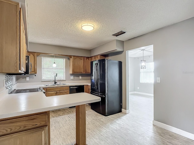 kitchen featuring sink, a textured ceiling, kitchen peninsula, pendant lighting, and black appliances