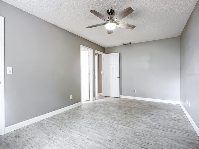 spare room featuring ceiling fan, light hardwood / wood-style floors, and a textured ceiling