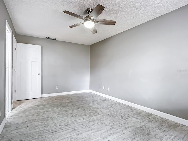 empty room with ceiling fan, a textured ceiling, and light hardwood / wood-style floors