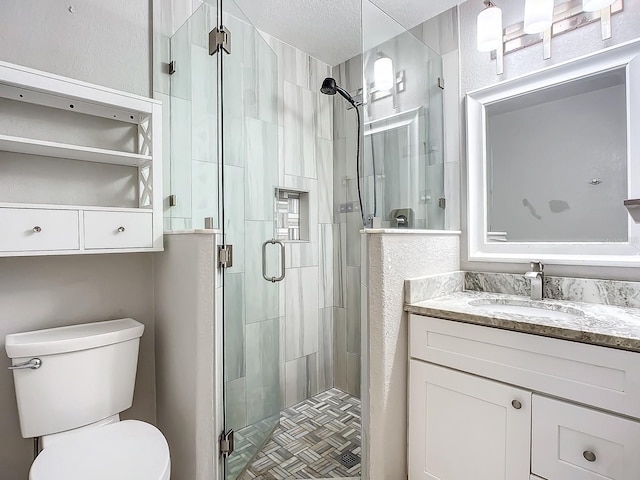 bathroom featuring a shower with door, vanity, a textured ceiling, and toilet